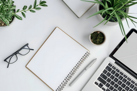 Clean and organized workspace with laptop, notebook, and plants.の写真素材