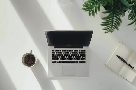 A serene workspace with a laptop, coffee, notebook and a plant.の写真素材