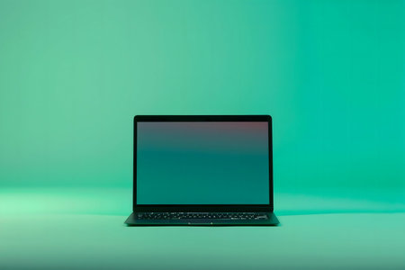 A sleek black laptop sits on a vibrant teal background. Minimalist aesthetic.の写真素材