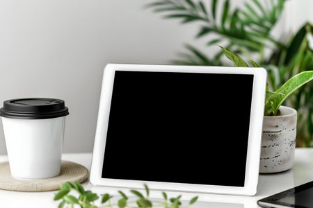 A clean, modern workspace mockup featuring a tablet, coffee cup, and houseplants. Perfect for...