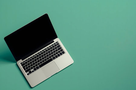 A sleek modern laptop rests on a teal background. Minimalist setup.