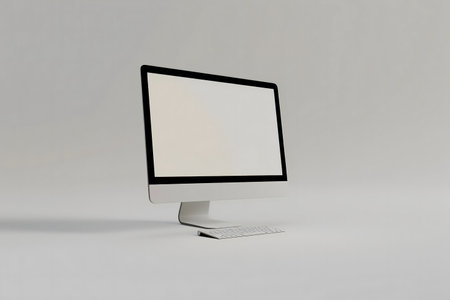 A sleek computer with a blank screen and a wireless keyboard, set against a simple gray background.の写真素材