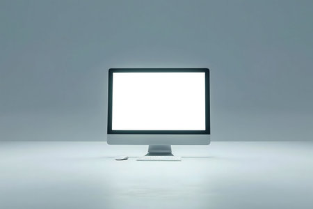 A clean, minimal image of a lit computer with a blank screen, keyboard and mouse.の写真素材