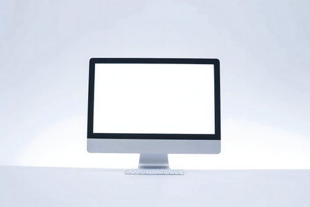 A sleek modern computer with a blank white screen sits on a white desk against a bright background. Minimalist setup.の写真素材