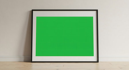 A simple, green artwork in a black frame rests on a wooden floor against a white wall.