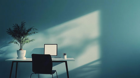 A minimalist home office bathed in sunlight, featuring a teal wall, simple desk, and calming atmosphere.の写真素材