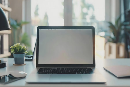 A clean workspace featuring a laptop, a plant, and a mouse on a bright desk.