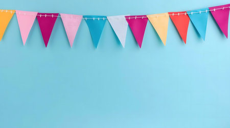 A string of colorful triangular flags hangs against a light blue background. Perfect for party invitations or celebration visuals.の写真素材