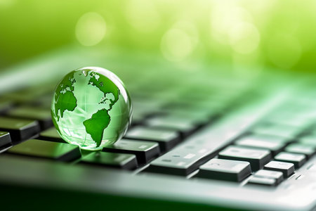 Green glass globe on a keyboard representing eco-friendly technology.の写真素材