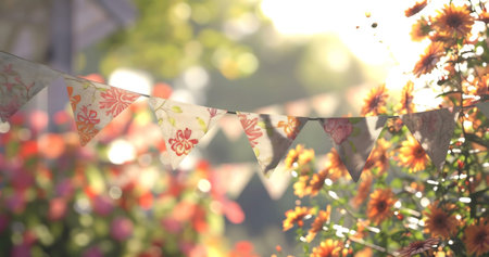 Floral patterns hang in a sunlit garden. Orange flowers add vibrant color.の写真素材