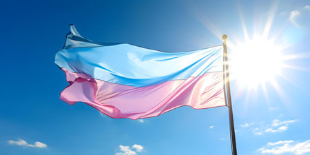 A vibrant transgender pride flag billows in a sunny sky.の写真素材