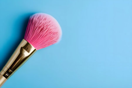 Close-up of a pink makeup brush against a blue backdropの写真素材