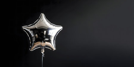 A single silver star-shaped balloon against a plain black backgroundの写真素材