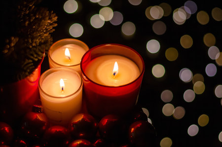 Burning candles and Christmas decorations on a dark background with bokeh