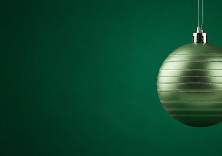 Green christmas bauble on a green background with space for textの写真素材