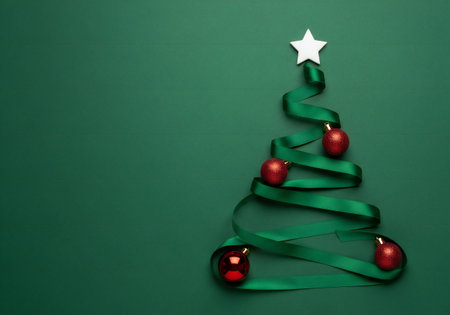 Christmas tree made of green ribbon and red baubles on green background