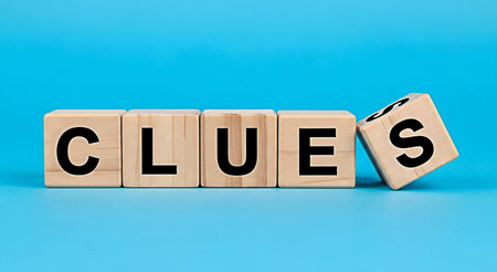 Wooden blocks with black letters spelling out the word clues on a blue surface