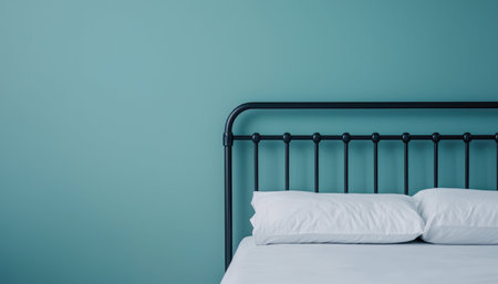 A bed with a black metal frame and white pillows against a teal wall