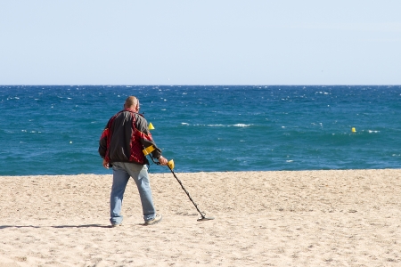 LLORET DE MAR, SPAIN - APRIL 30  Unidentified man looking for lost objects with a metal detector in Lloret de Mar, a famous touristic destination in Mediterranean coast, on April 30, 2012, in Lloret, Spainの写真素材