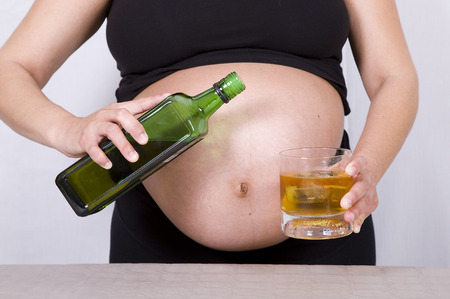 Pregnant woman drinking whiskyの写真素材