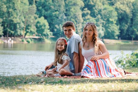 Family concept: woman, man and daughter sitting in the park. Summer outdoorsの写真素材