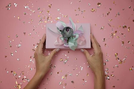 Beautiful gift box on festive pink background in female hands