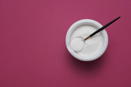 collagen protein powder in a bowl with a modern spoon on purple background