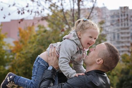 Father playing with his little daughter, throwing her up, having fun. Autumn outdoorsの写真素材