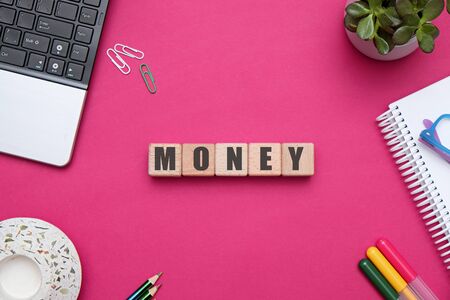 Flat lay composition with wooden cubes with MONEY letters at office workspace on red tableの写真素材