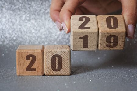 New year 2019 change to 2020 concept. Hand flip over wood cube block on silver backgroundの写真素材