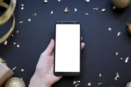Smartphone in the middle of christmas composition in black and gold, flat layの写真素材