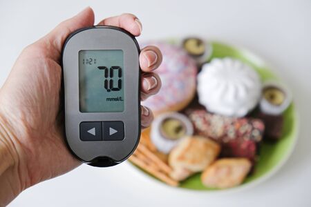 Diabetes concept: sweets and unhealthy food with glucometer. Nutrition cause diabetic deseaseの写真素材