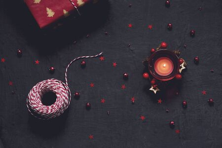 Black festive background with red decoration, candle and gift, Chrtistmas and new year greeting card with place for textの写真素材