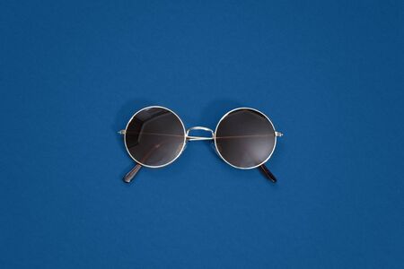 Round retro gold sunglasses on classic blue background - color of the year 2020