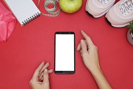Composition with smartphone and sport equipment- Sneakers, tape measure, glucometer on red...