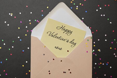 Valentine day: envelope with hearts and text I LOVE YOU on black background and confetti