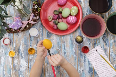 Close up of childs hands coloring easter eggs with egg dye. View from above