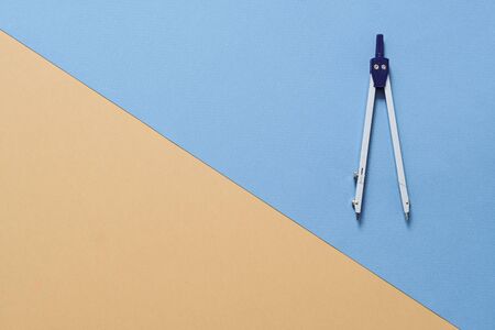 Drawing Compass Isolated on blue and beige geometric background, copy space. Geometry, mathematics