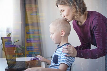 Young programmer writing code on a computer together with his mom or teacher. Programming lessons for kids.の写真素材