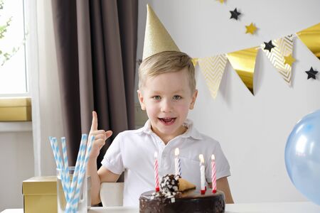 Happy boy celebrating birthday alone and blowing lighting candles on a cake
