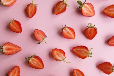 Pink background with fresh strawberry halves, top viewの写真素材