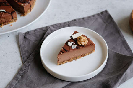 Piece of homemade chocolate raw vegan cake - healthy dessert made from coconut milk, butter, cashew,...