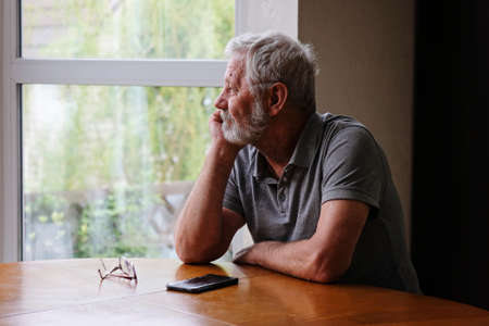 Senior retired man sitting at home alone while quarantineの写真素材