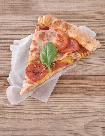 Delicious fresh pizza with ham and tomato on a wooden background.の写真素材