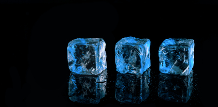 three blue ice cubes on black backgroundの写真素材