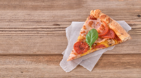 Delicious fresh pizza with ham and tomato on a wooden background.の写真素材