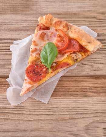 Delicious fresh pizza with ham and tomato on a wooden background.の写真素材