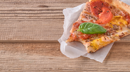 Delicious fresh pizza with ham and tomato on a wooden background.の写真素材