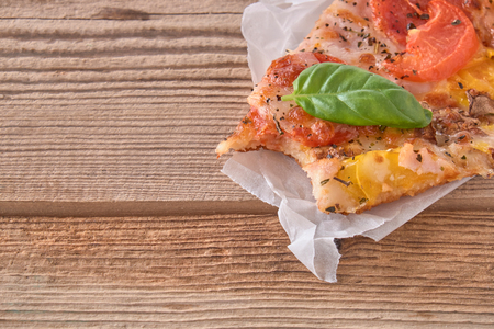 Delicious fresh pizza with ham and tomato on a wooden background.の写真素材