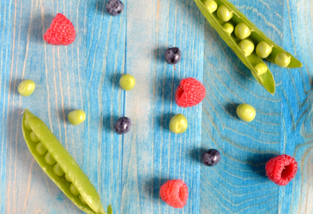 peas and berries on a blue wooden backgroundの写真素材